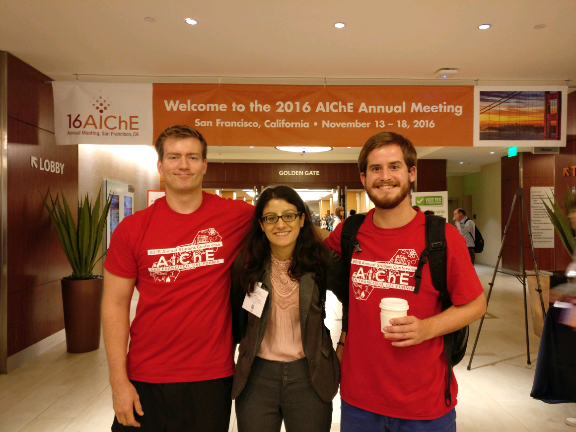 Three students standing in front of a banner that reads 'Welcome to the 2016 AIChE Annual Meeting'