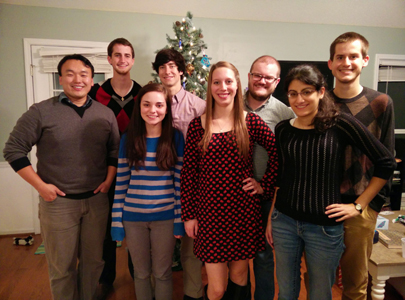 A group of eight people standing in front of a Christmas tree
