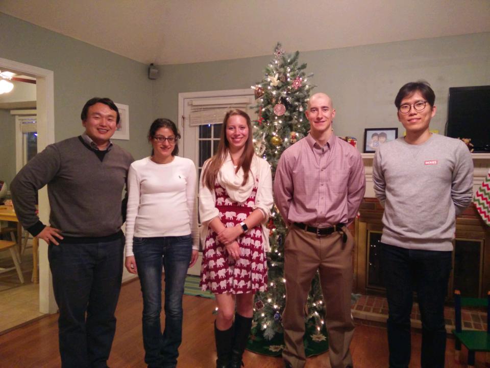 A male professor and four students standing in front of a Christmas tree