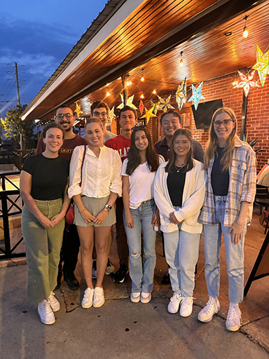 Group photo of people in front of a restaurant with lighting