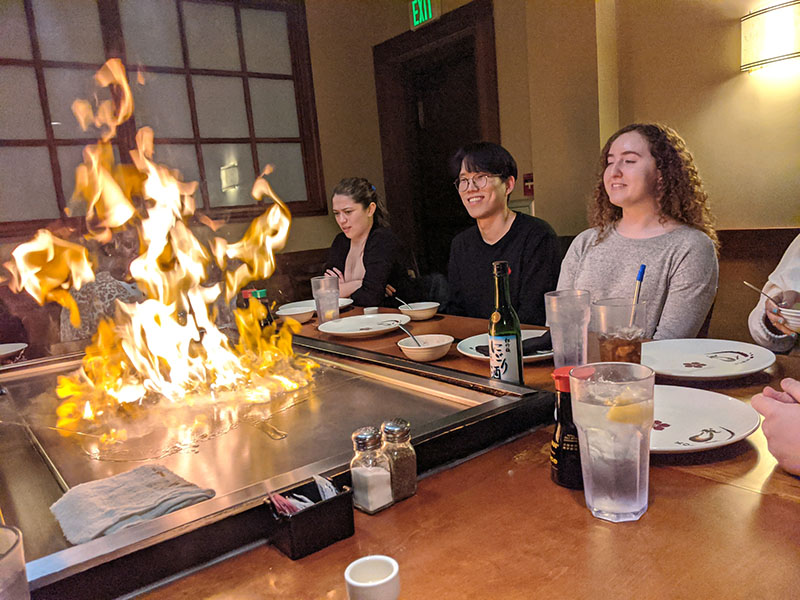Three students eating a hibachi dinner with fire show