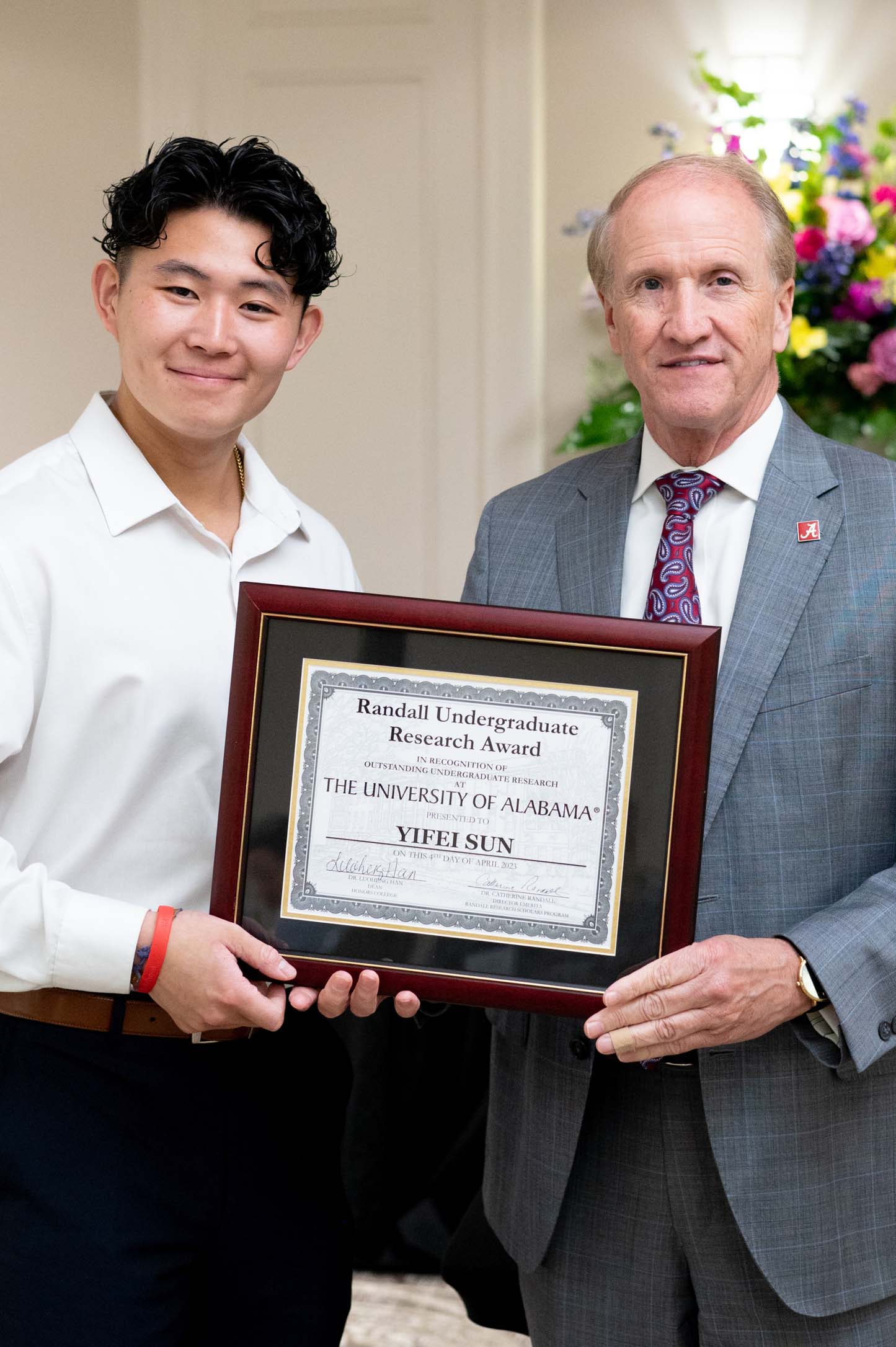 Yifei Sun and President Bell standing next to each other holding a plaque