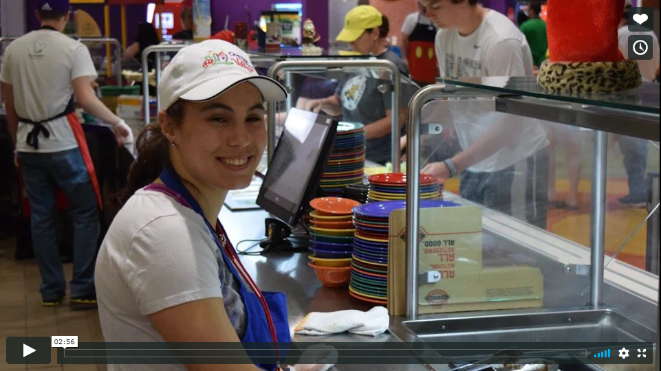 A female student smiling and serving at a caffeteria