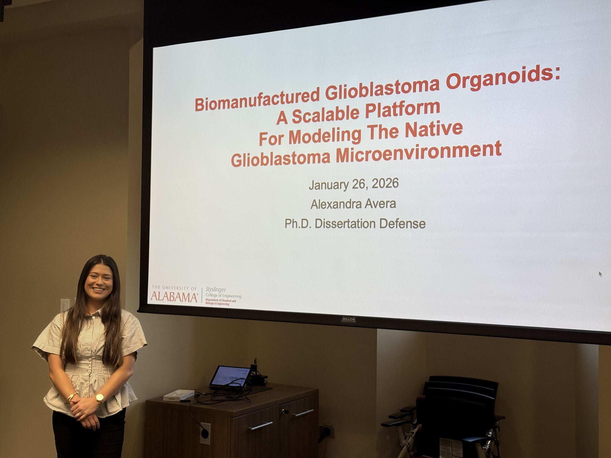 A female student standing in front of a screen with powerpoint slide