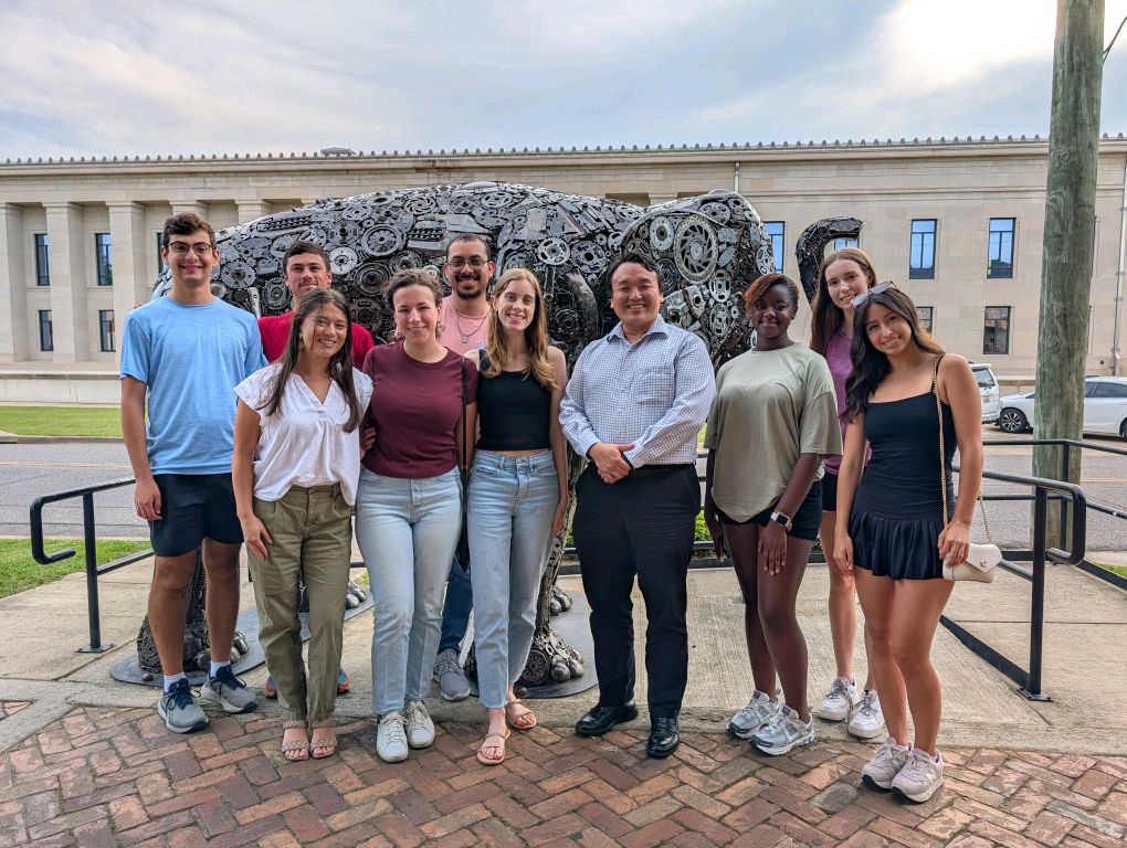 Group of students and professor in front of metallic elephant