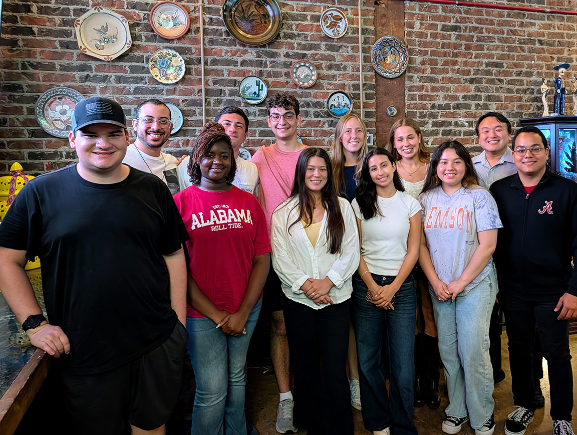 Group photo of people in front of a wall of plates