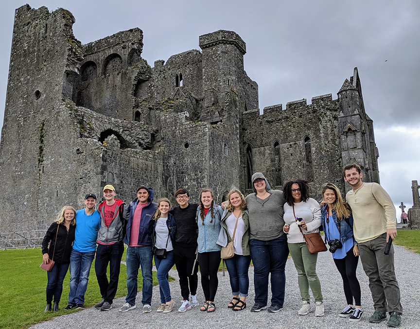 A group of students standing in front of a 12th century cathedral at Cashel, Ireland